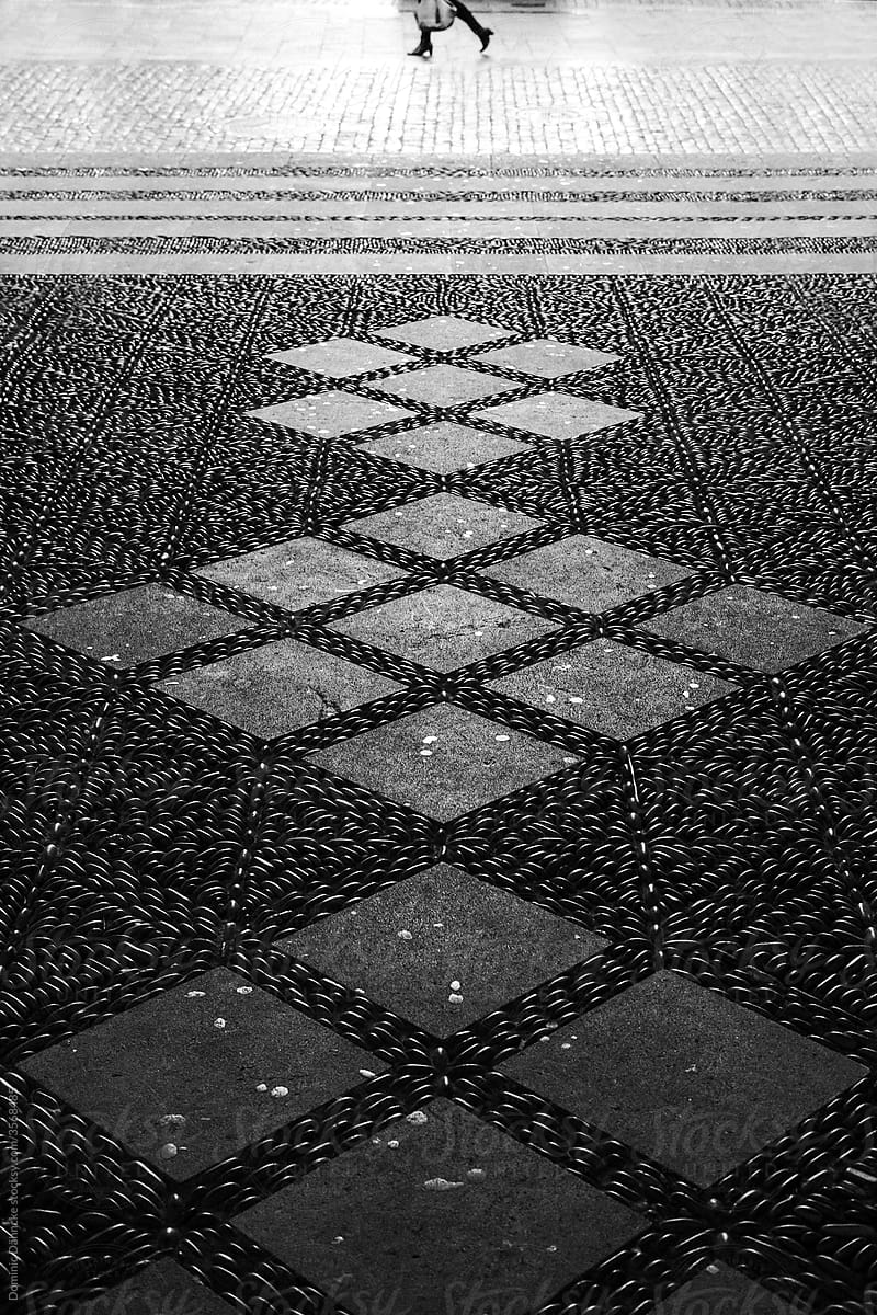 Cobbled floor patterns with a woman\'s legs.