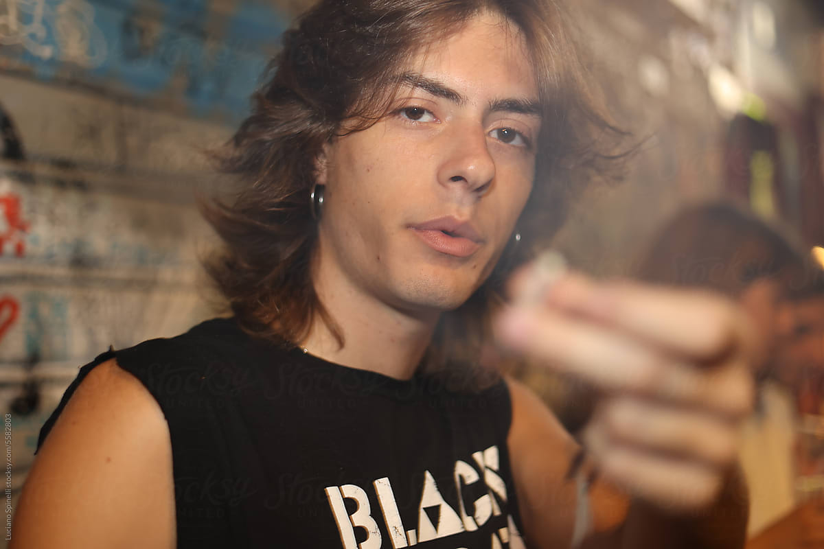Rock musician wearing band T-shirt smoking and offering cigarette