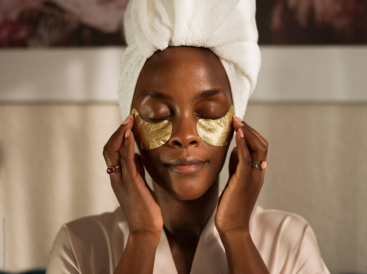 Black woman applying eye patches after shower