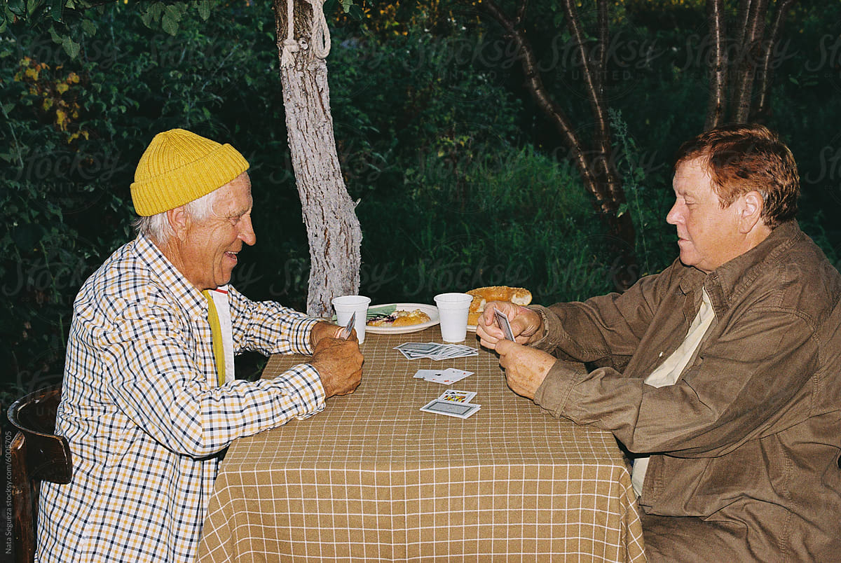 An elderly couple is involved in an outdoor card game