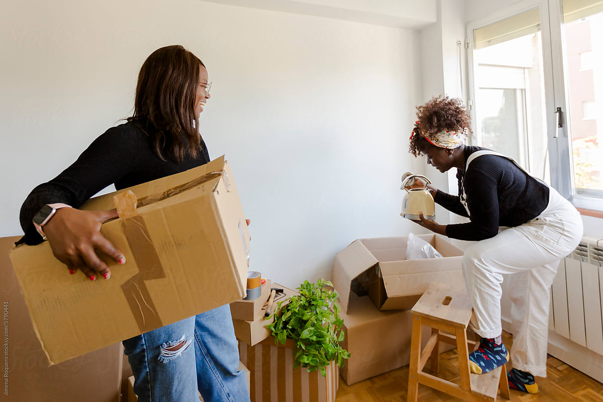 Two women unpacking boxes moving in a new home
