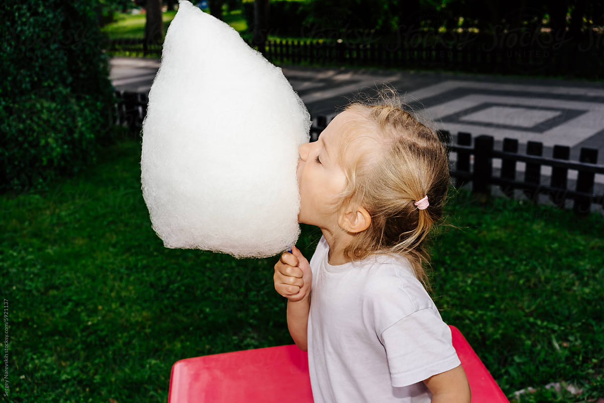 Child biting massive cloud-like cotton candy