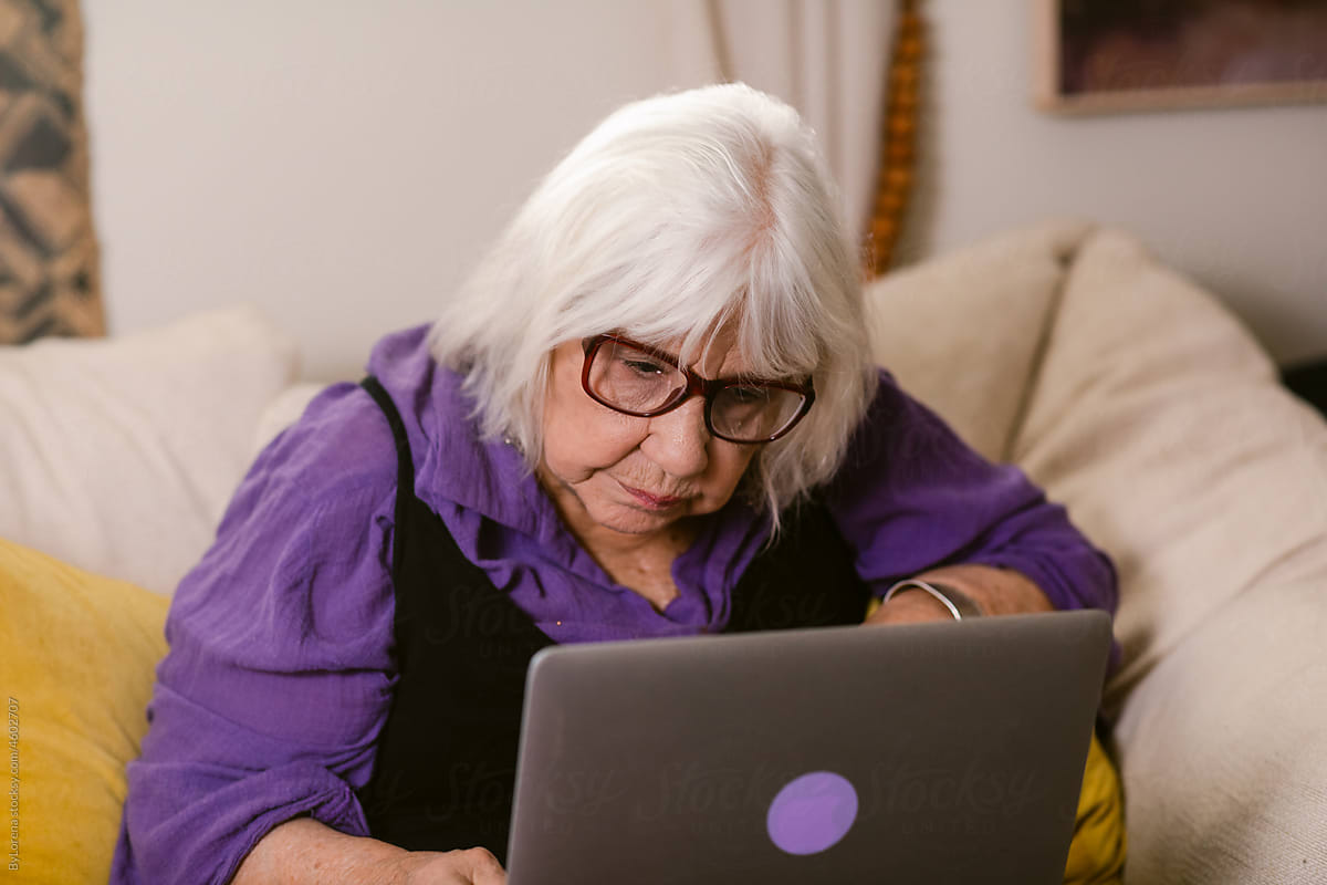 Modern elderly woman with laptop at home