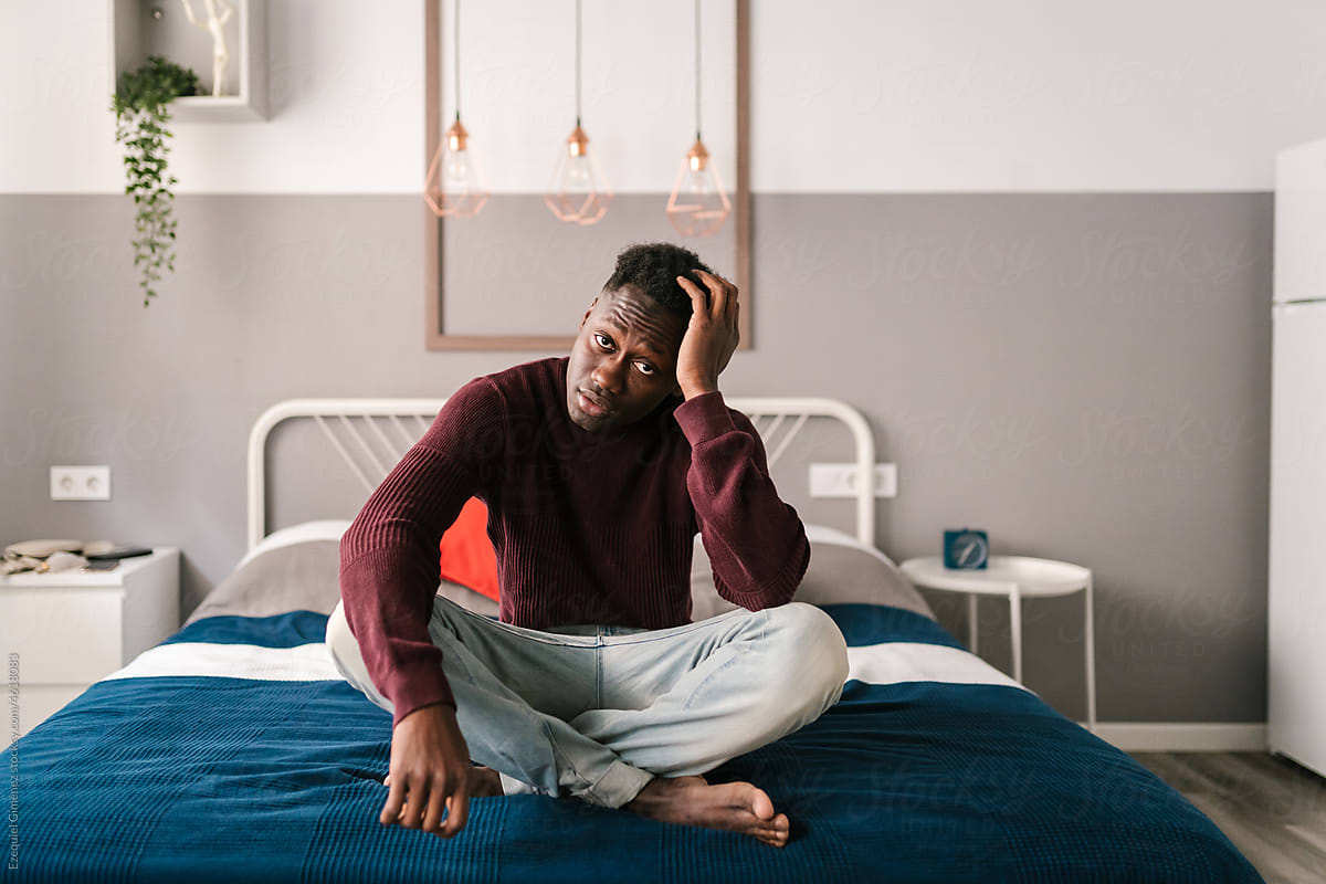Depressed black man sitting on bed