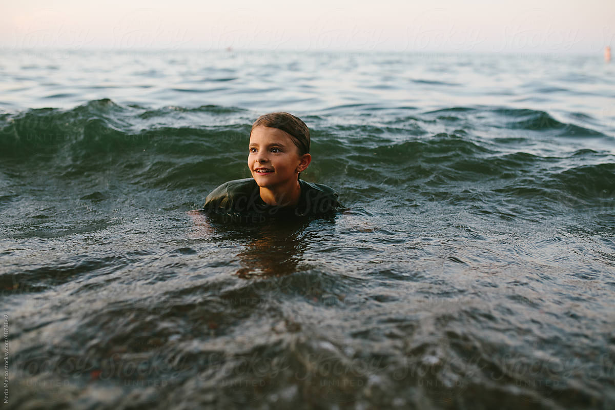 smiling young girl swims in lake