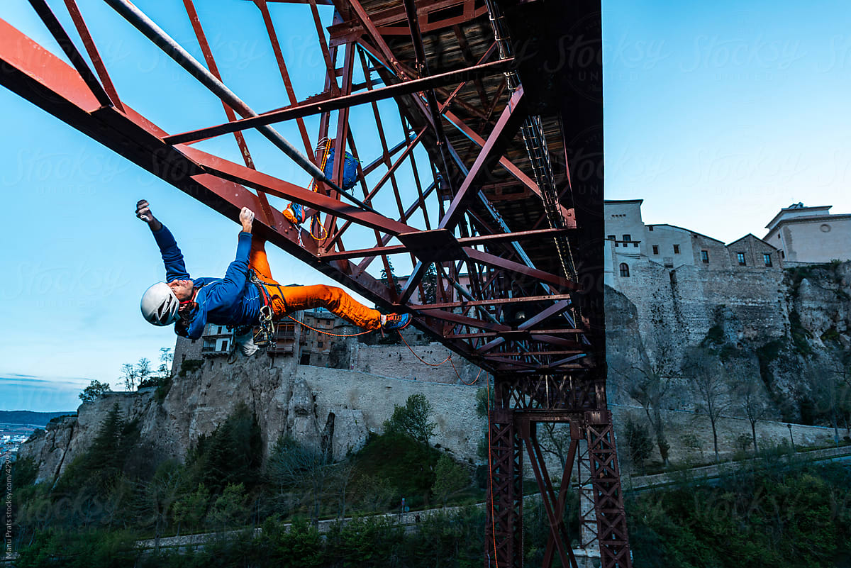 Authentic man rock climbing a metal bridge in the city