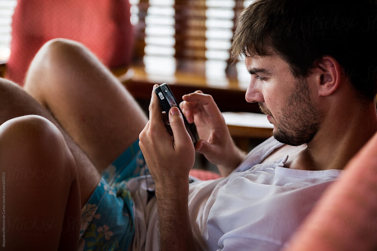 Young man in shorts checking cell phone on holiday