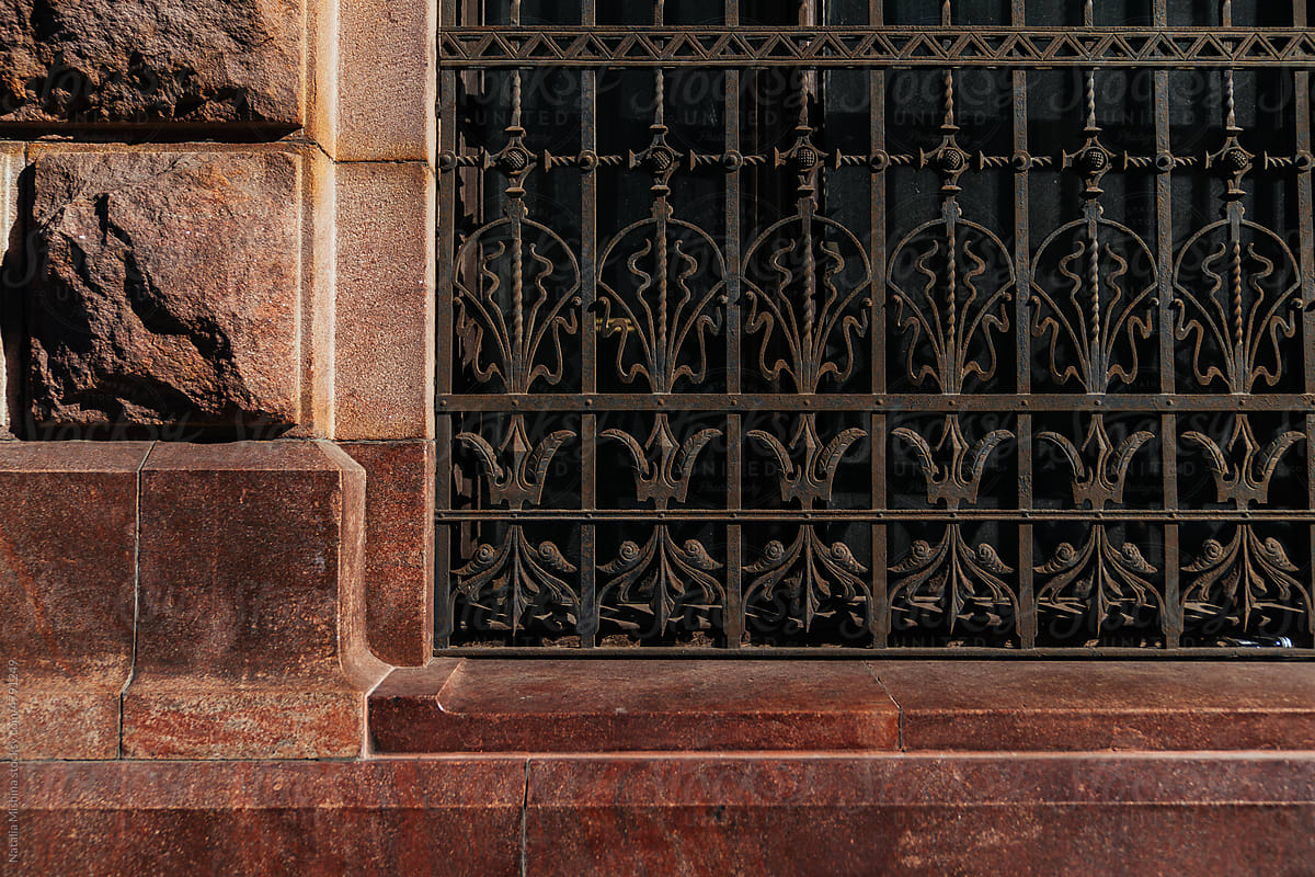 A fence on the facade of a strict granite building.