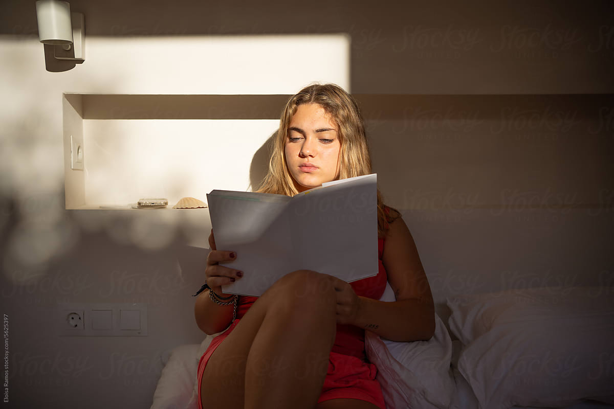 young woman reading a book at bedroom