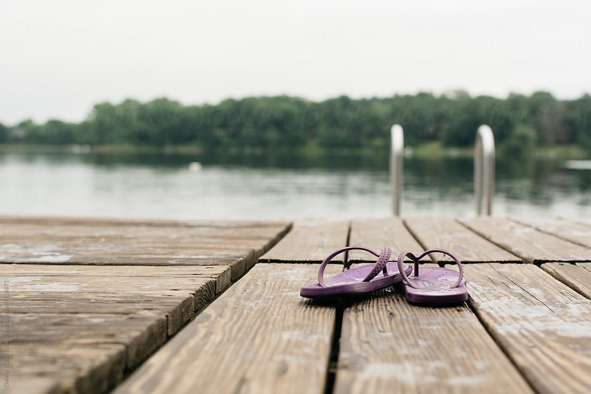 Pair of purple flip flops on a deck by a lake
