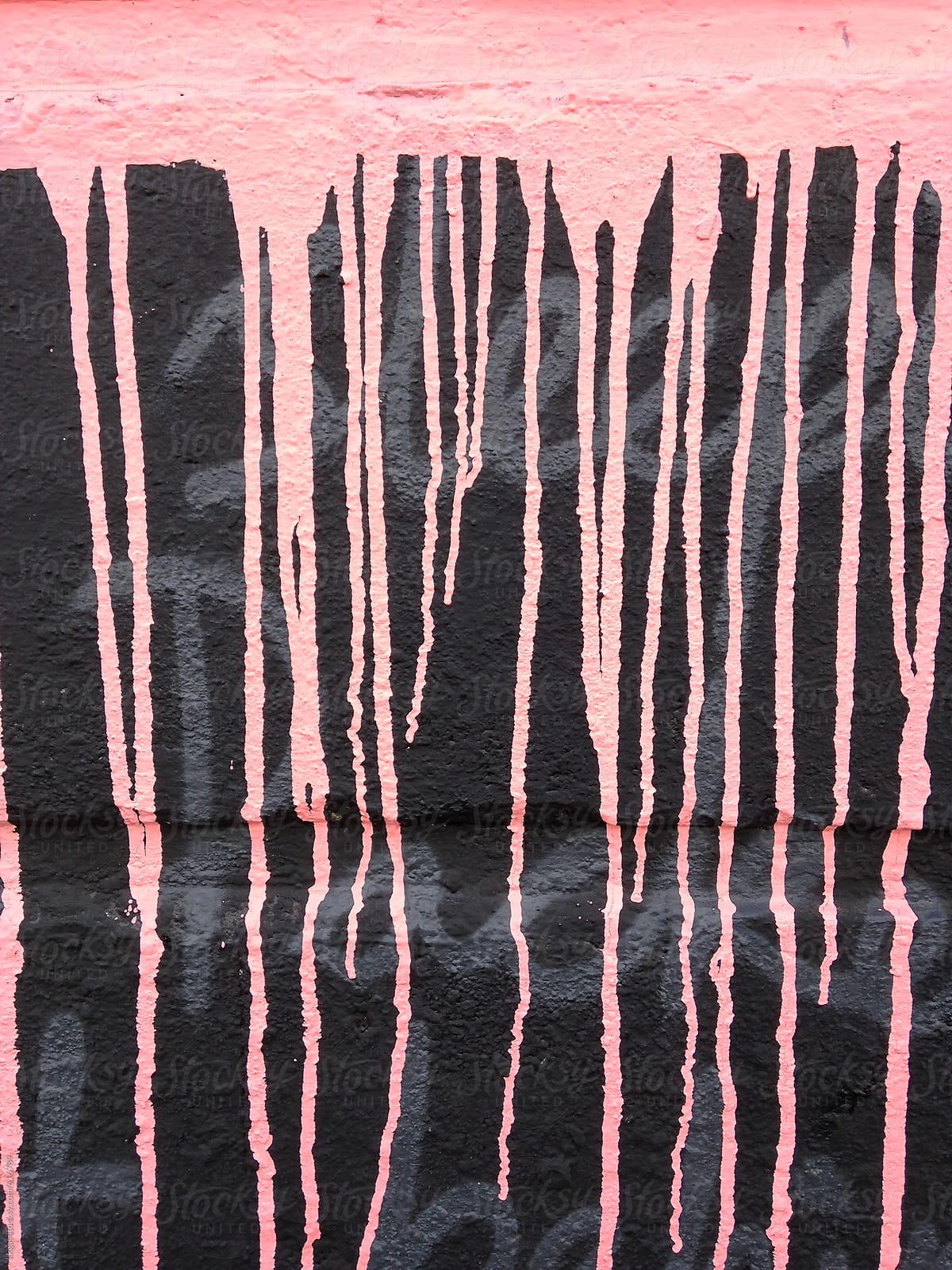 Pink paint splashes running over hand writing on a black wall