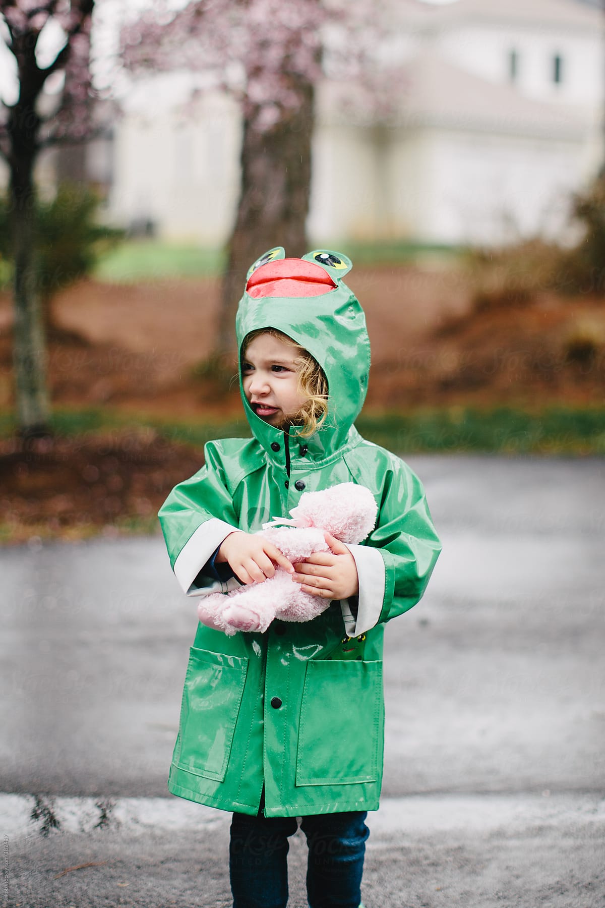 Toddler in a raincoat playing in the rain