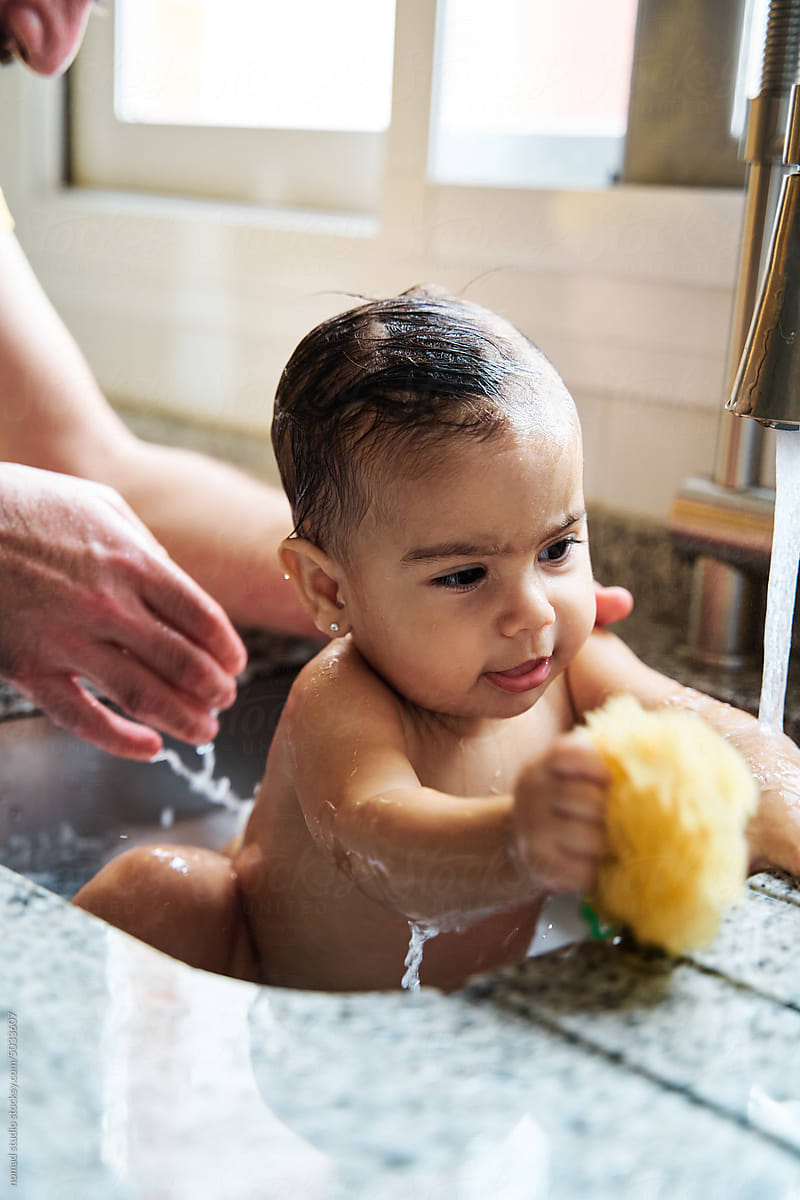 Baby bathing in the kitchen at home.