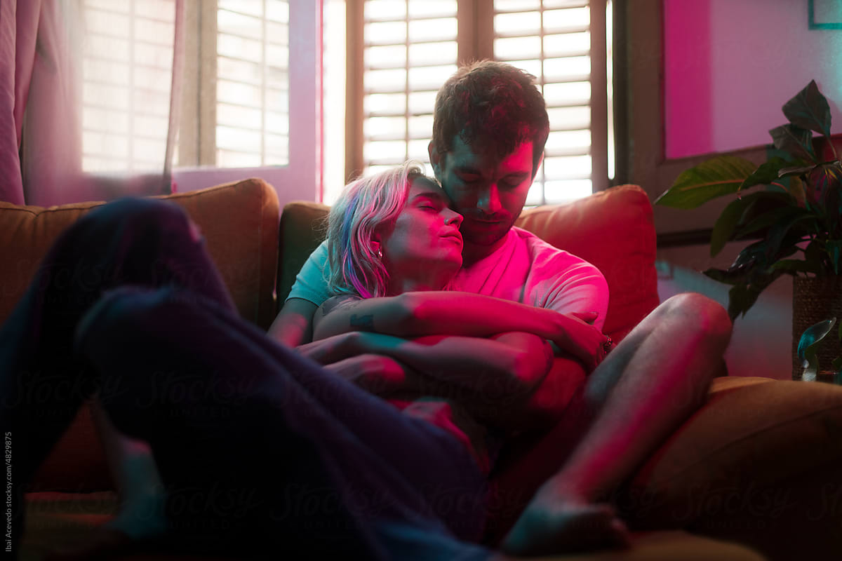 Intimate lovers hug on the sofa with neon lighting