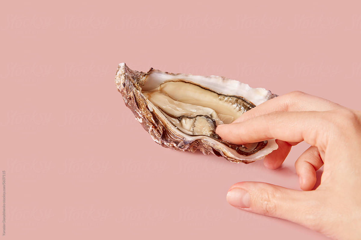 Close up of female fingers touching fresh open oyster inside