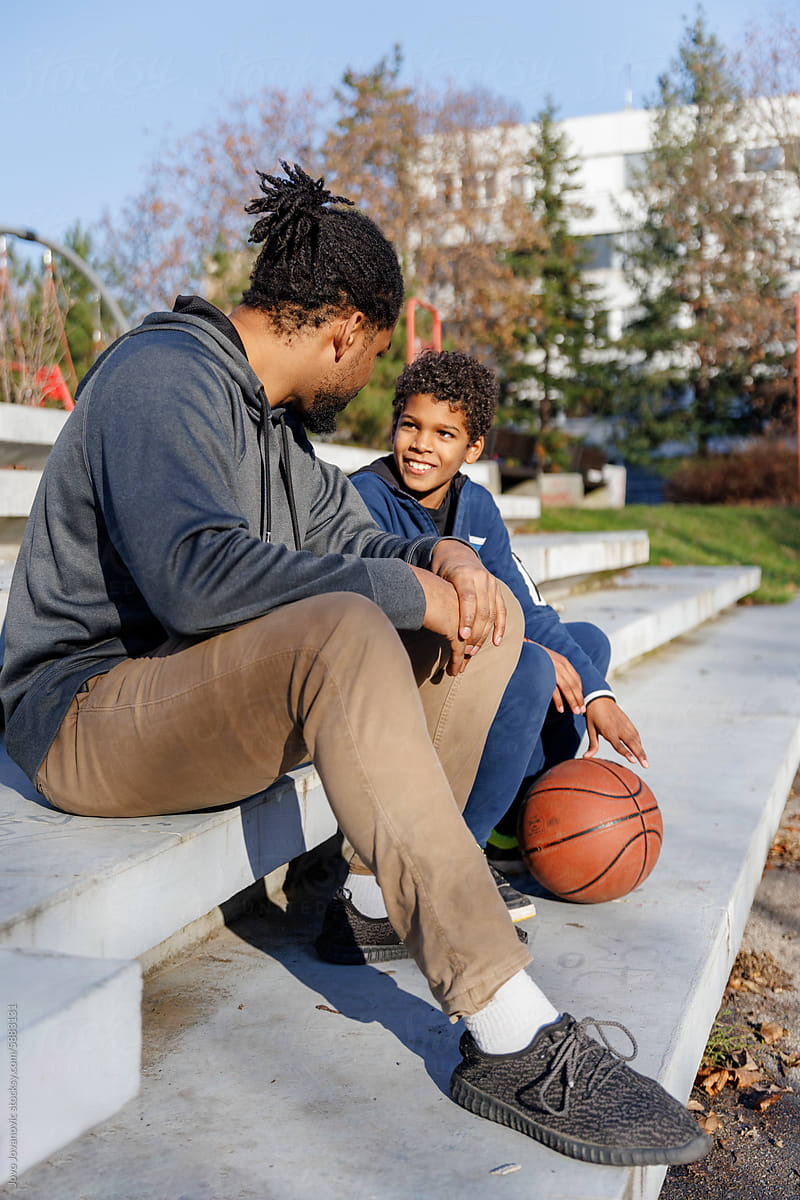 Happy son is talking with father on basketball court