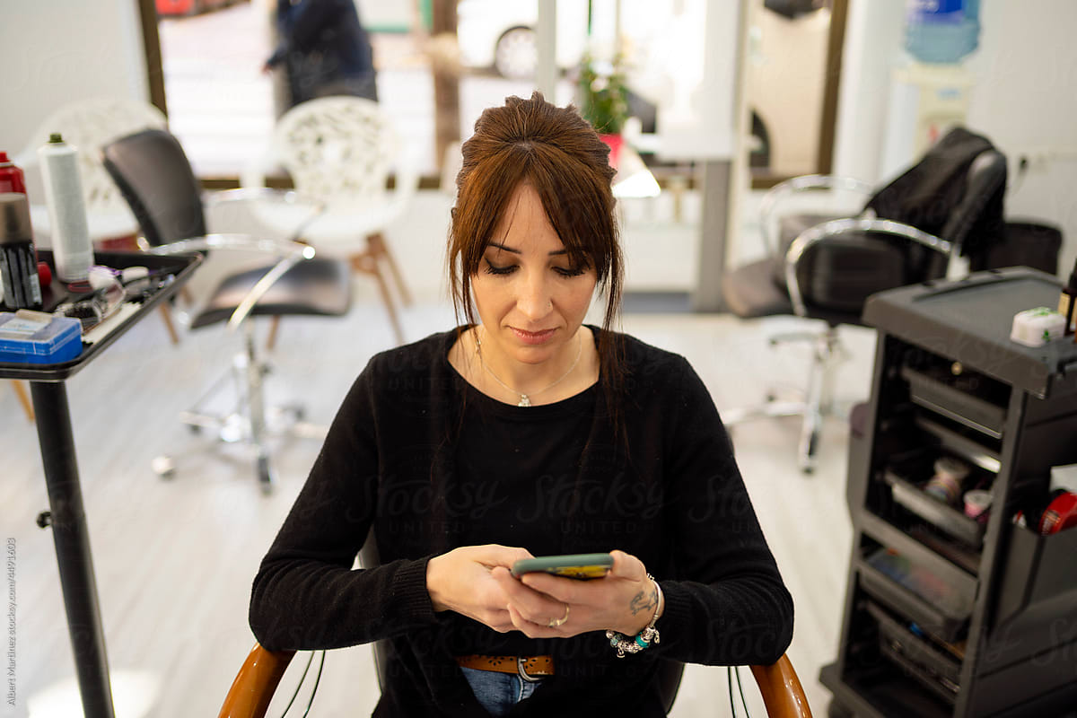 Woman using smartphone in beauty salon