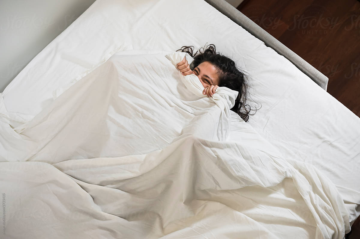 Woman wrapped in white sheets in the bed
