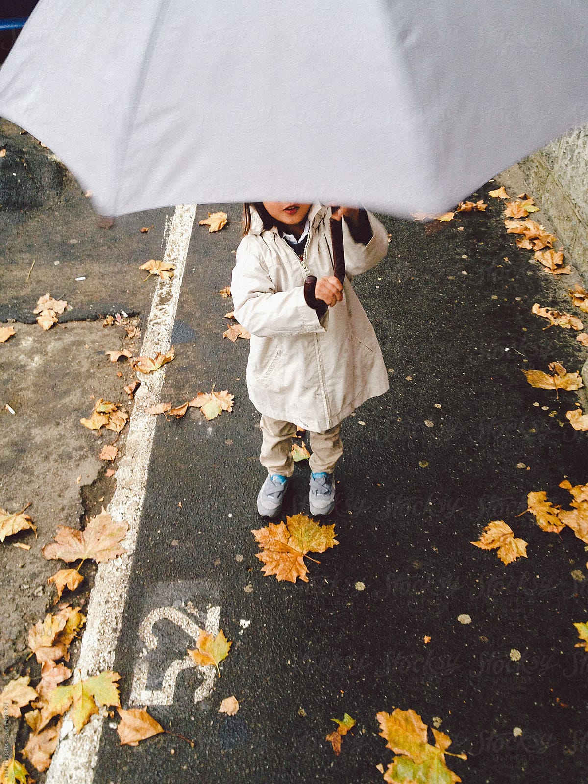 Cute little boy playing with umbrella in on the street