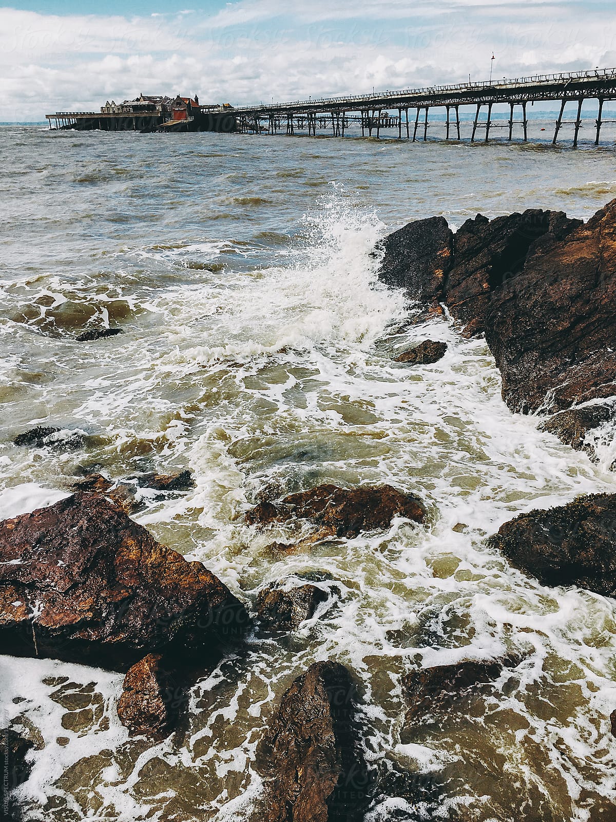 Rocky Ocean Shore With Deserted Grand Pier In Background\