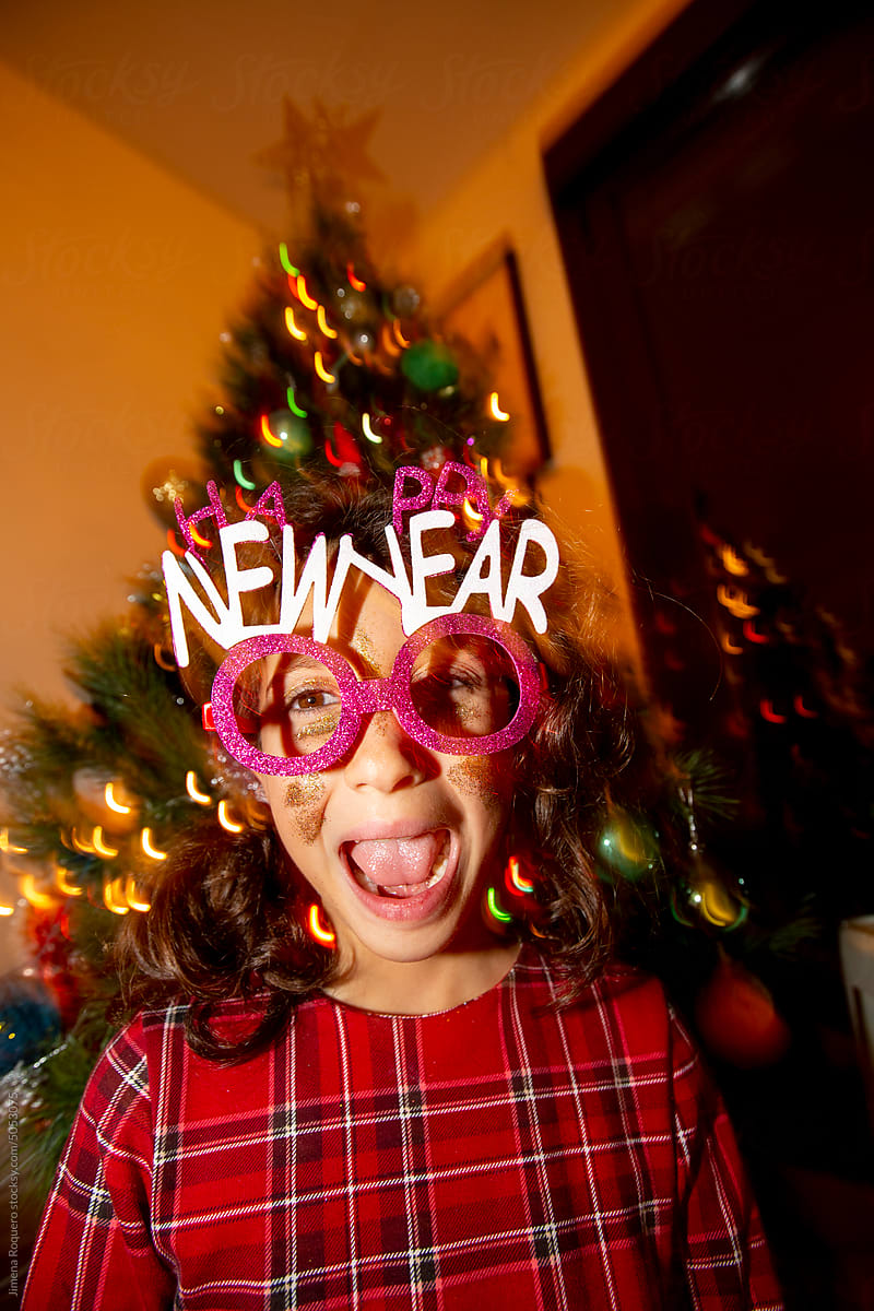 Kid making funny faces with Happy New Year party glasses