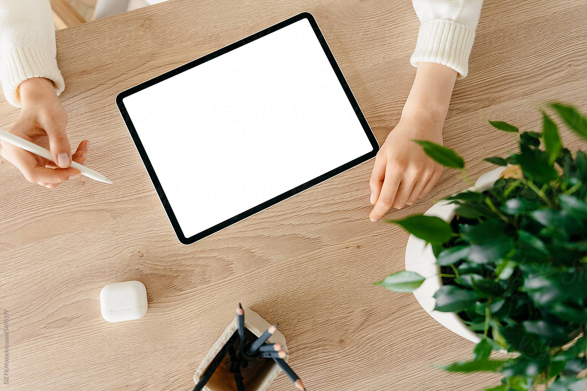 A woman uses a tablet with a white screen