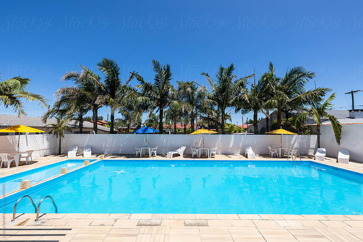 Swimming pool in hotel with cristal clear water, tables beach umbrella
