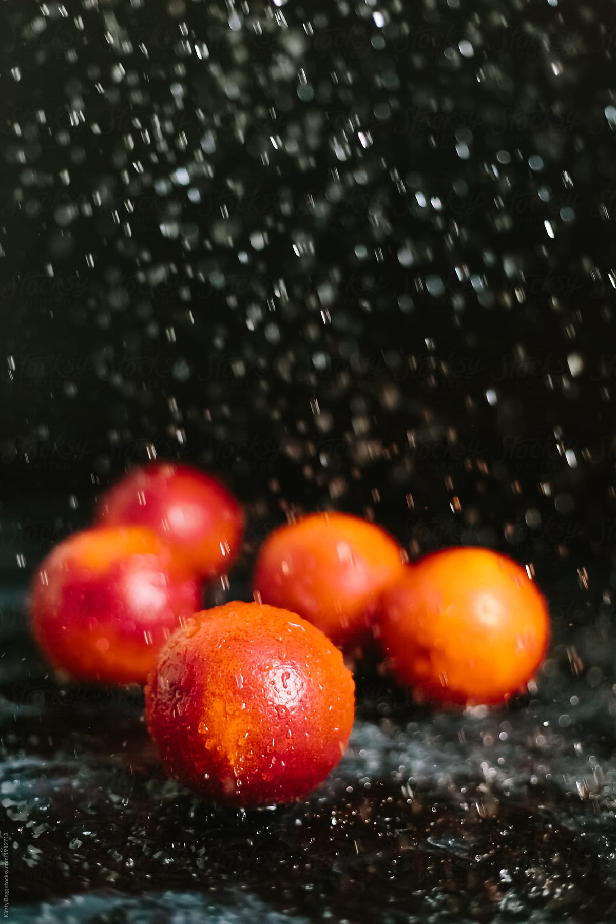 Water droplets falling onto whole red oranges