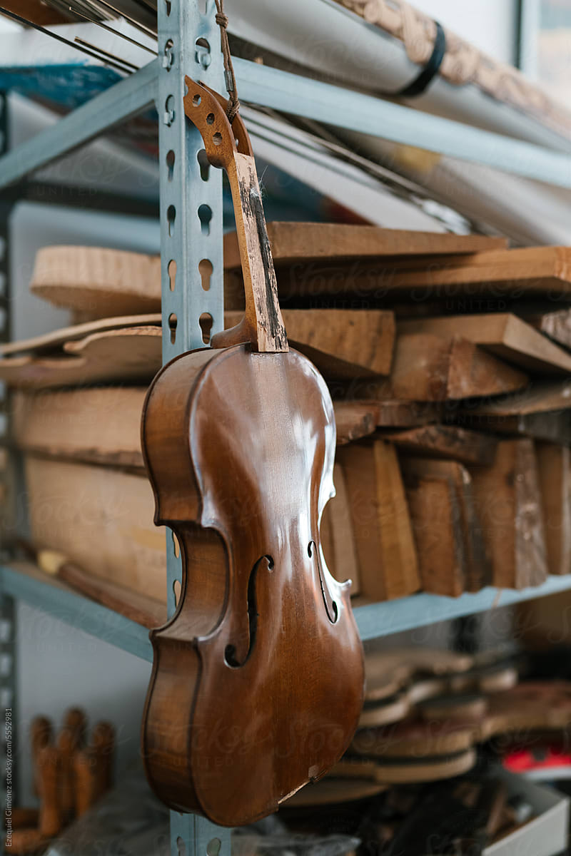 Old violin hanging on rack in workshop
