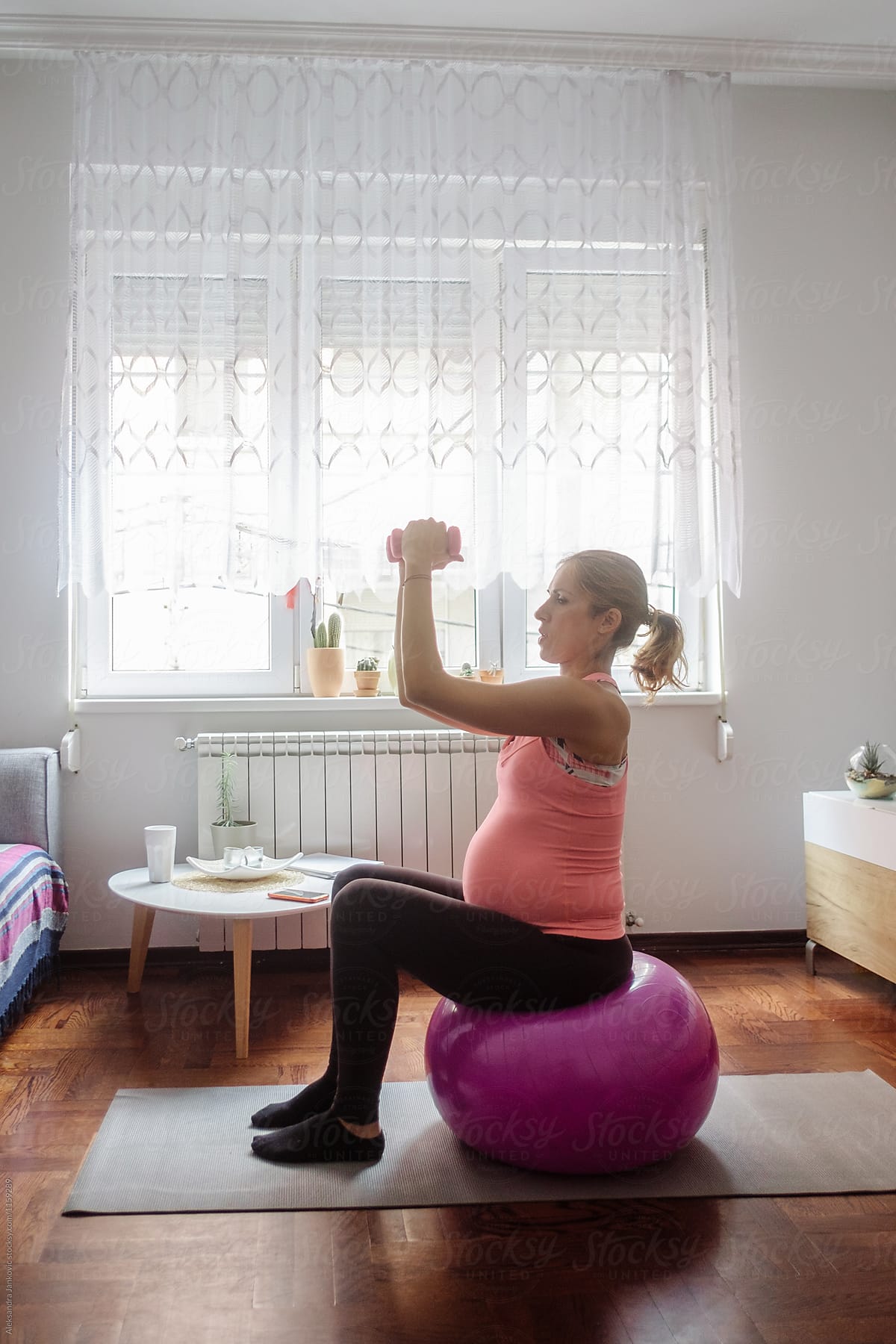 Pregnant Woman Sitting On The Pilates Ball And Working Out At Home