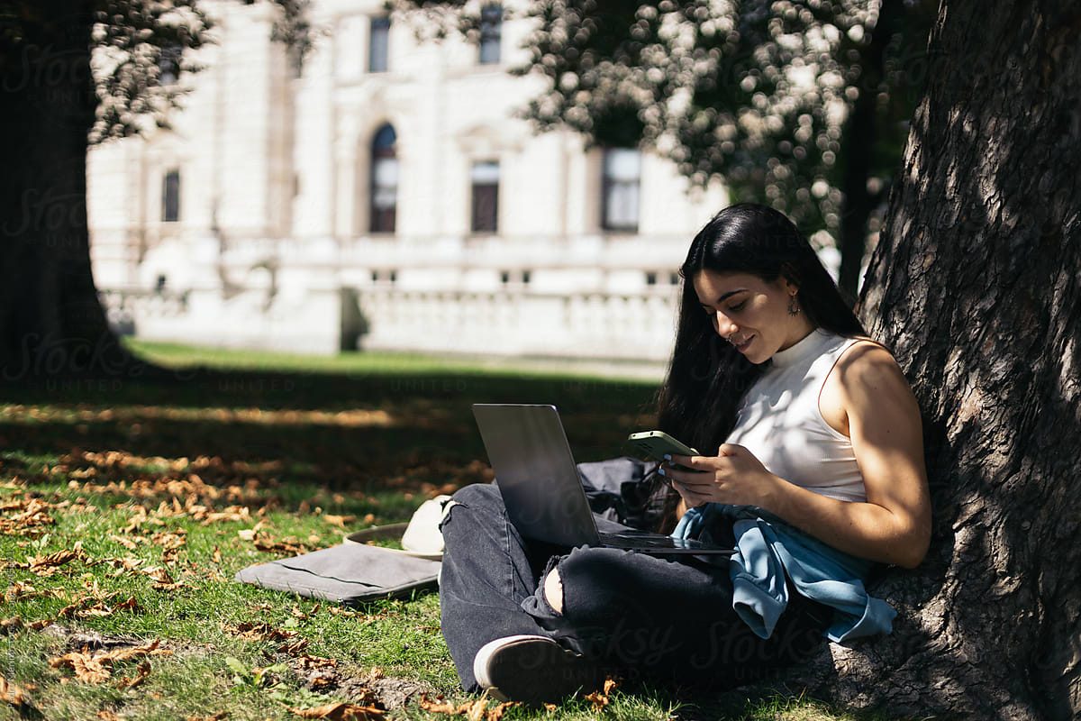 Young woman using laptop and smartphone outdoors
