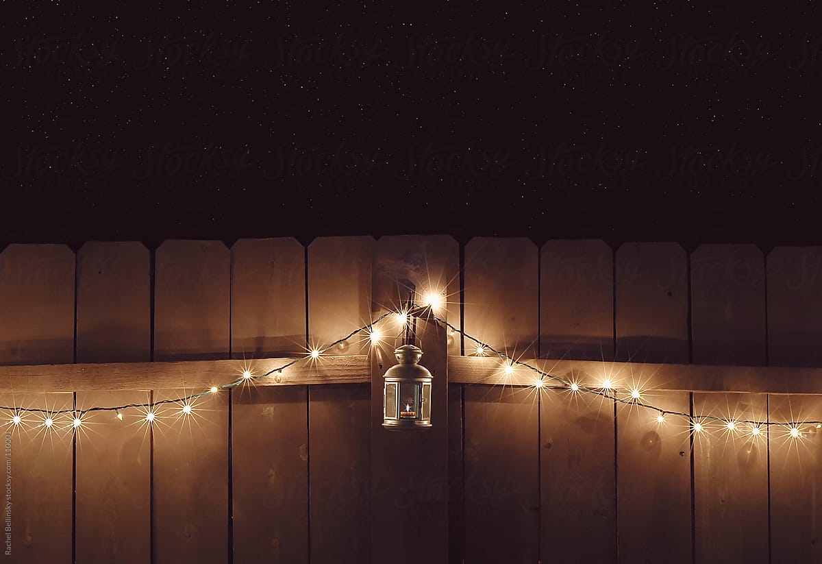 Christmas lights draped on a fence at night with lantern