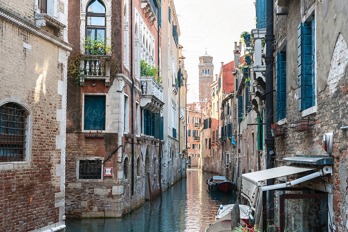 Street with water canal with boats and historical buildings in Venice