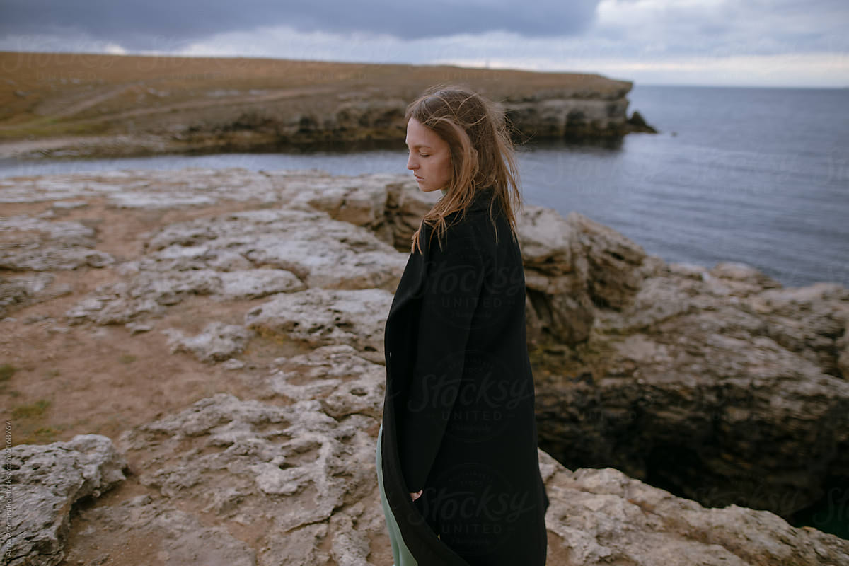 Portrait of a young girl in a black coat near the sea
