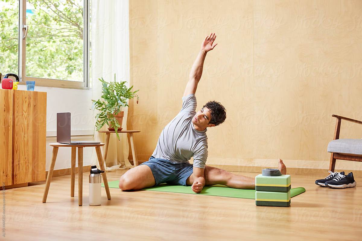 Fit guy doing Parighasana pose during online yoga class
