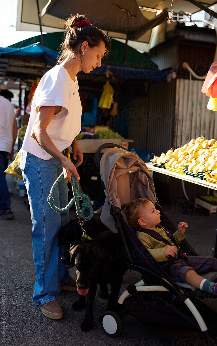 Young woman at the market with her son and dogs