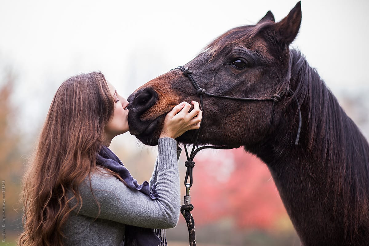 Woman kissing her horse outside on the field