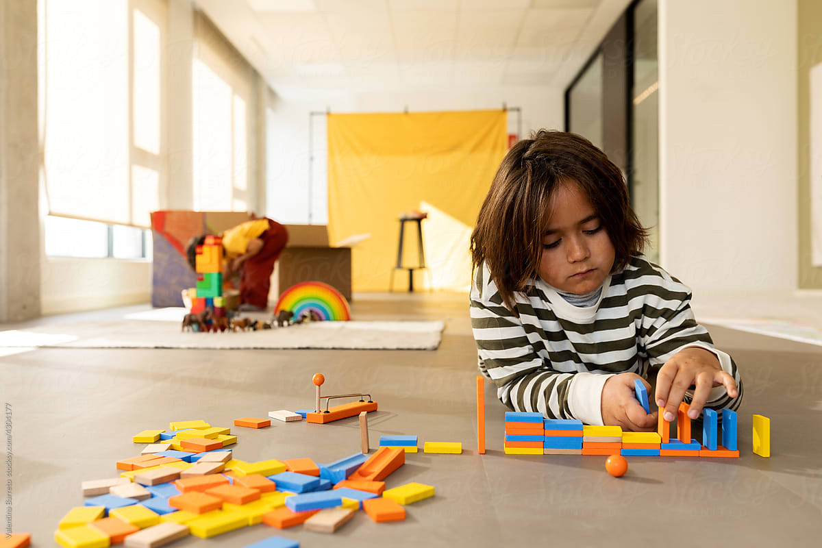 Boy playing with wooden dominoes in playroom