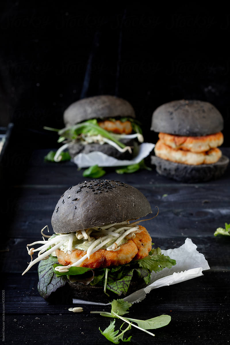 Black bun fish burger with salad and sprouts