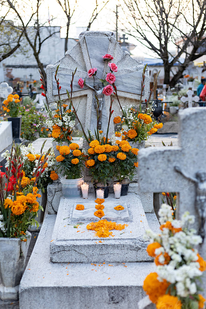 A Grave Decorated With Flowers And Candles