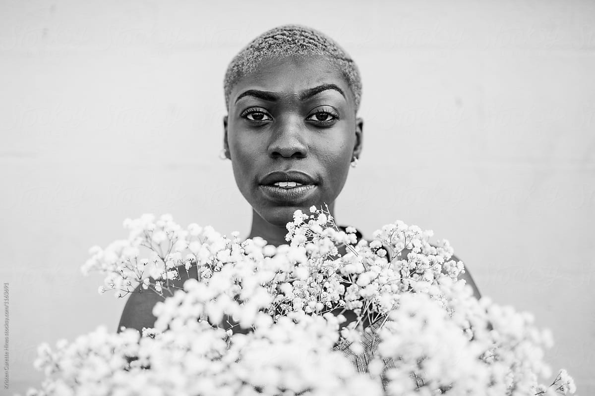 A black and white portrait of an African American woman holding babys breath flowers.