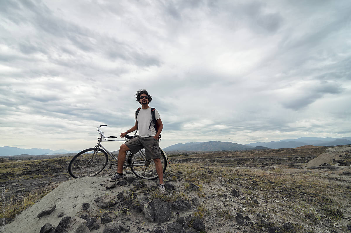 Guy next to his bicycle in rocky terrain of desert
