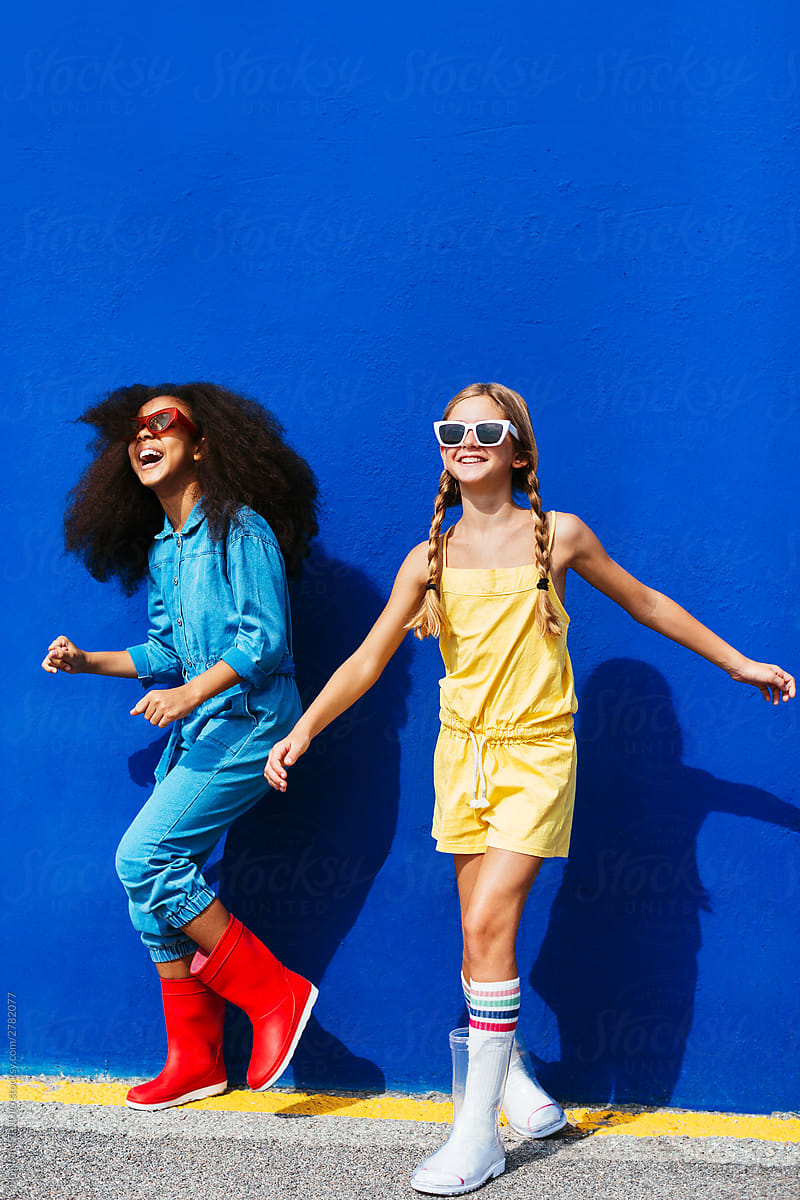 Trendy multiethnic friends in sunglasses holding having fun on street