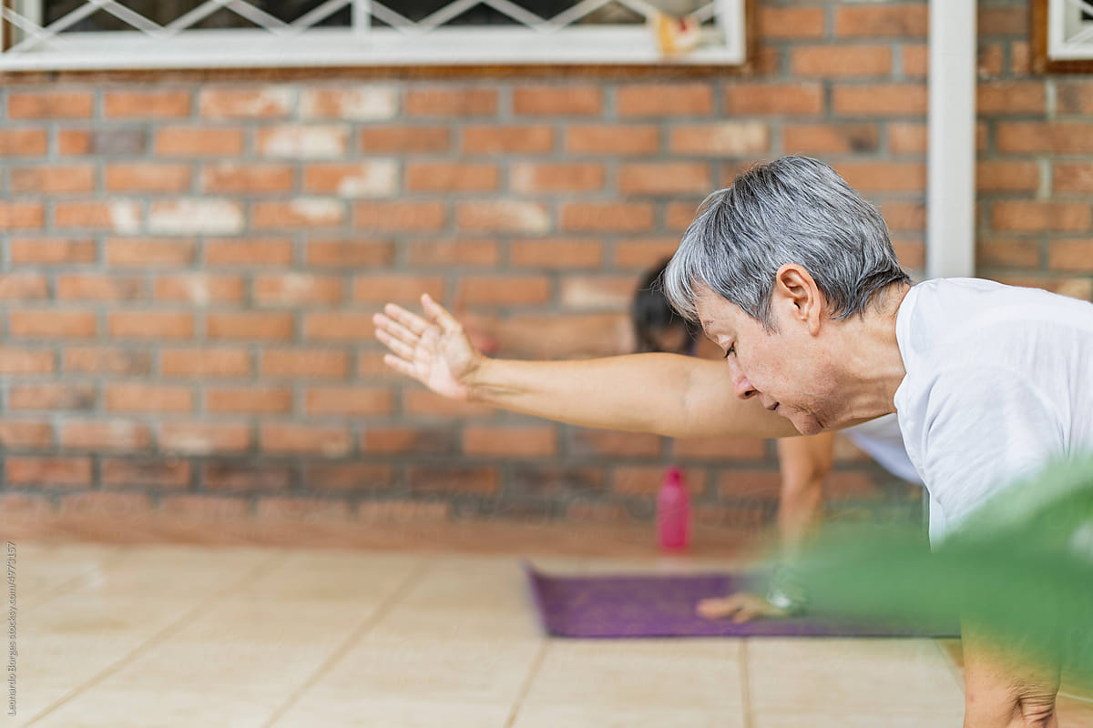 Older adult by performing yoga positions with his stretched arm