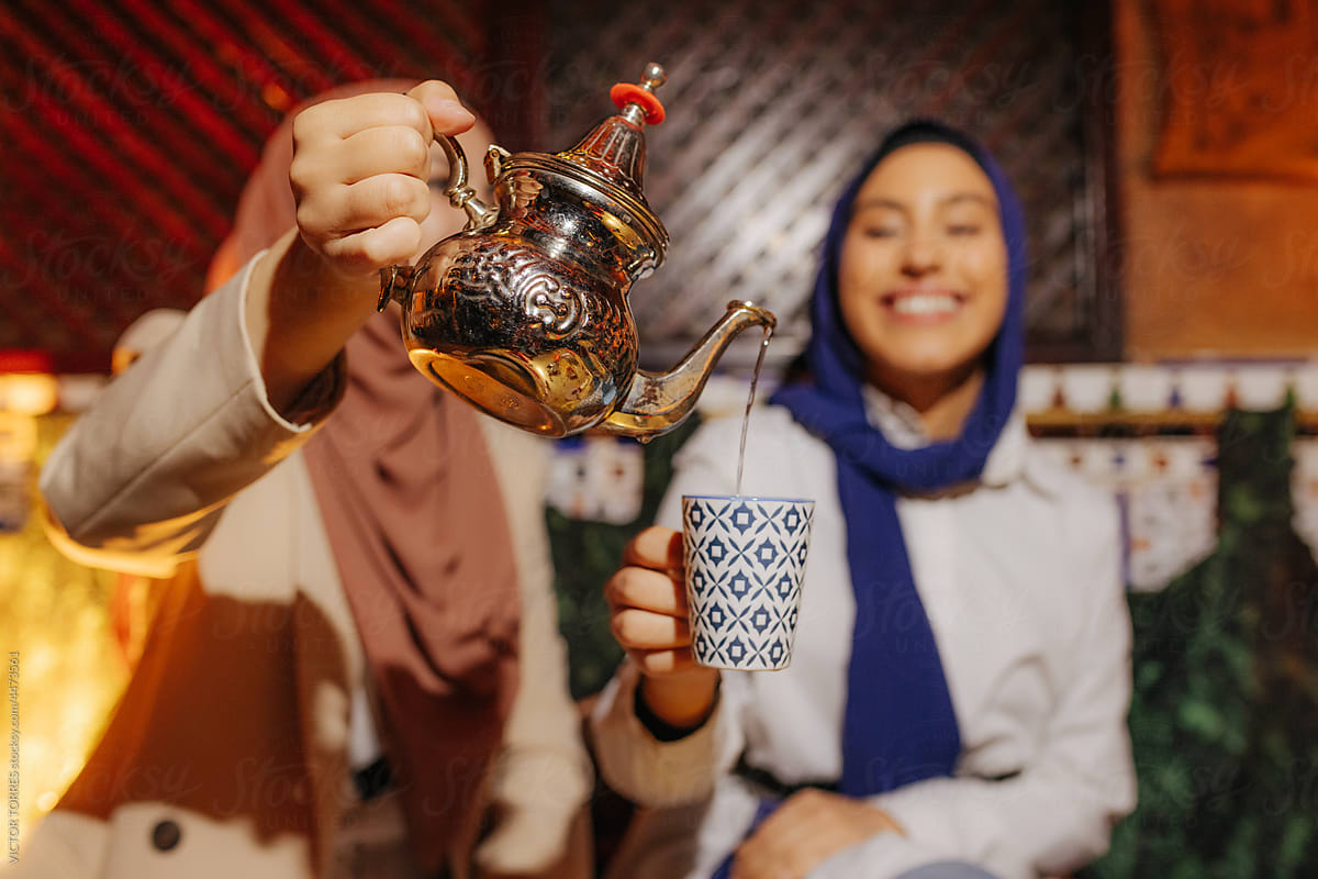 Cheerful Muslim women serving tea