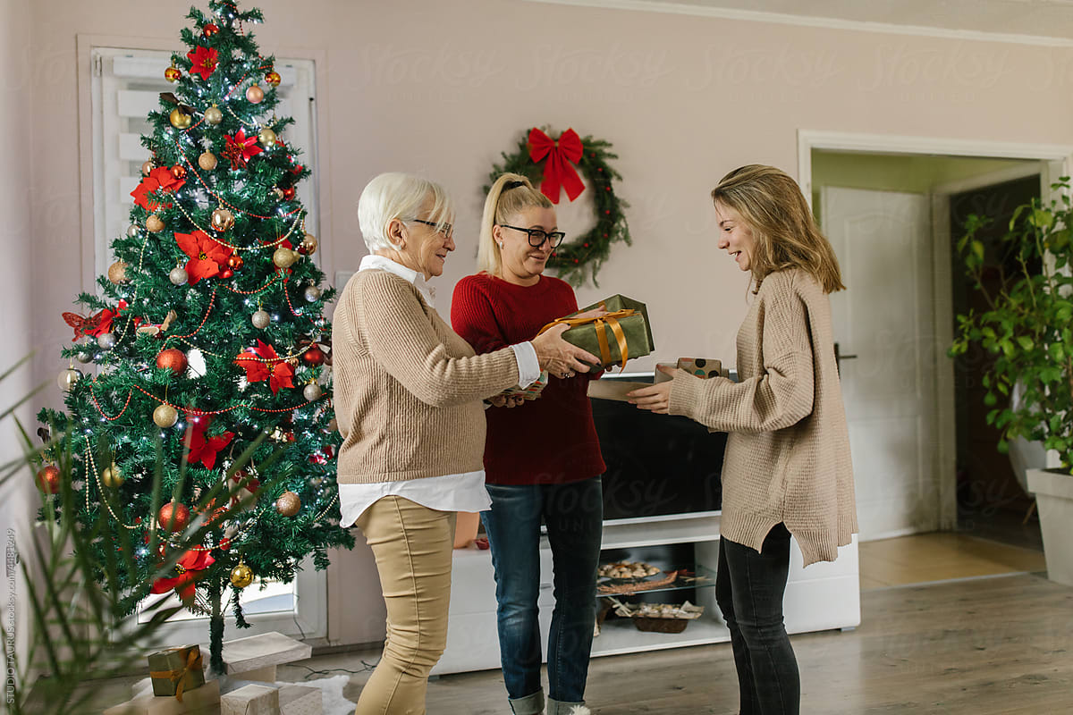 Women smiling and exchanging Christmas gifts at home