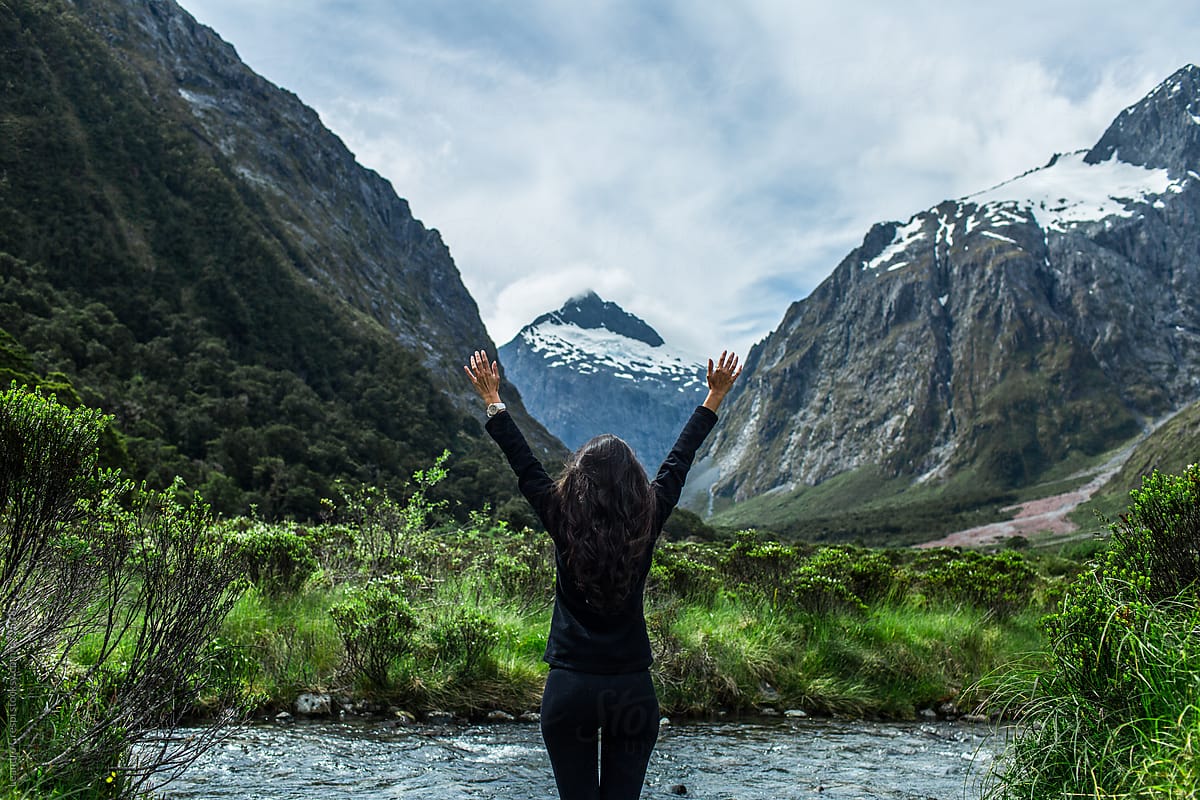 A woman from behind forming a V with her arms, watching the mountains