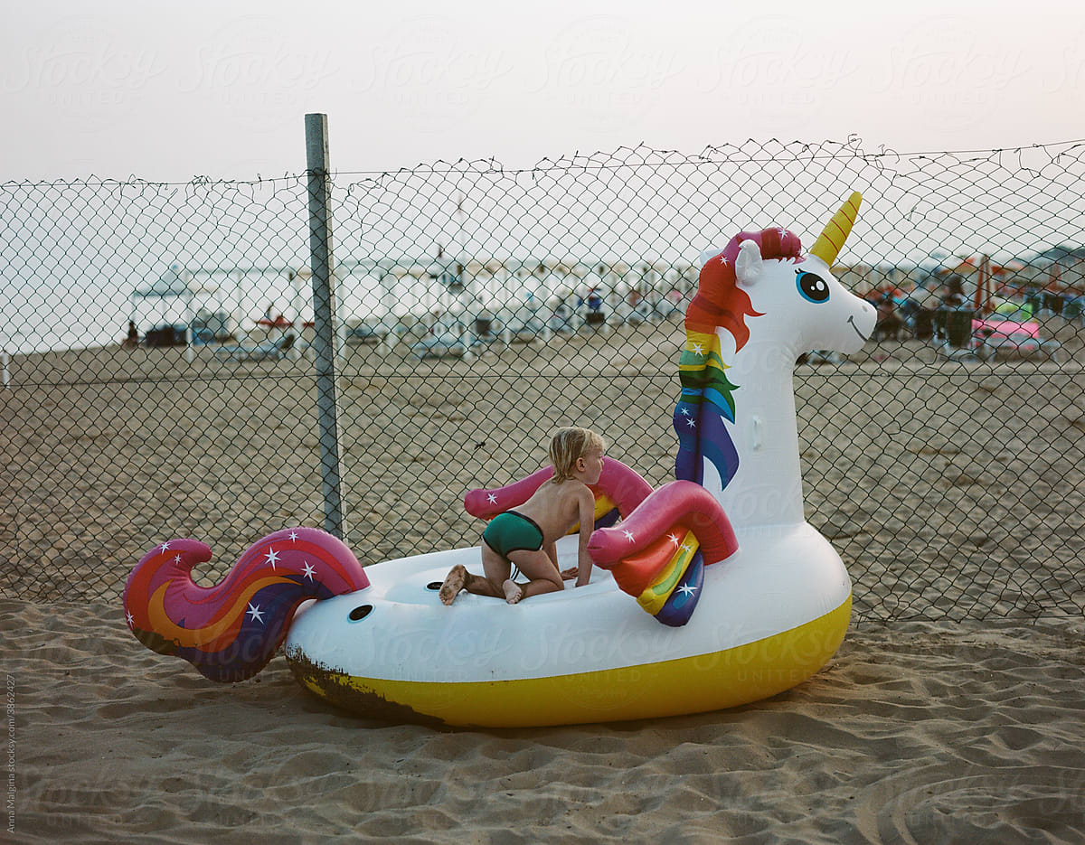 Toddler riding on inflatable unicorn on beach