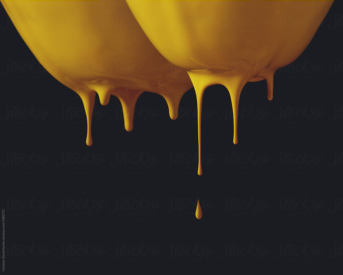 Drops of yellow paint flow from the pear on a black background