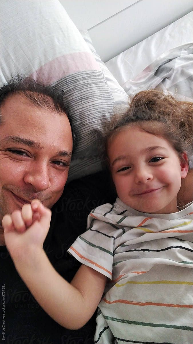 Ugc selfie of dad and daughter lying in bad